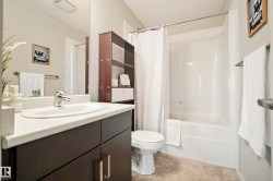 Bathroom featuring a white vanity countertop, undermount sink, dark wood-finish cabinetry, a built-in shower/tub combination, and tiled flooring - 