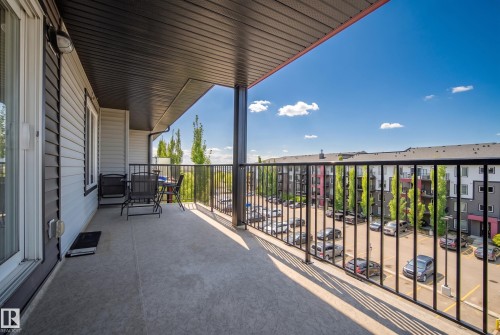Spacious outdoor balcony with concrete flooring, black metal railings, and a dark soffit ceiling - #419 5515 7 Av Sw, Edmonton, AB 