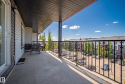 Spacious outdoor balcony with concrete flooring, black metal railings, and a dark soffit ceiling - 