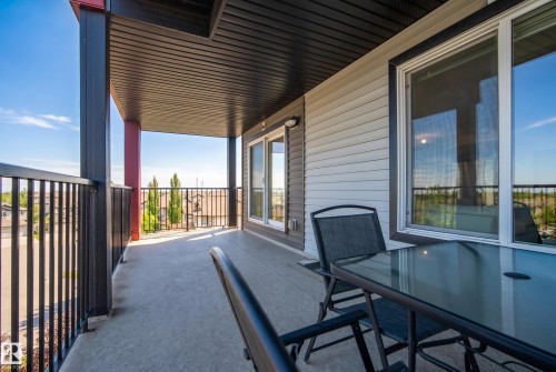 Covered balcony with concrete flooring, black metal railings, and a horizontal siding exterior - #419 5515 7 Av Sw, Edmonton, AB 