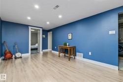 Spacious room with striking periwinkle walls, recessed ceiling lighting, and light wood-finish flooring throughout - 