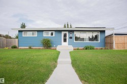 Modern ranch-style home featuring a fresh blue exterior with horizontal siding, expansive front-facing windows, and a welcoming entry with glass door - 