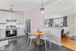 Kitchen featuring stone-look floor tiles, white shaker-style cabinetry, and stainless steel appliances - 