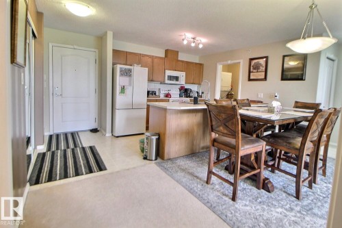 Kitchen featuring wood-finish cabinetry, stainless steel appliances, and an eat-in island with countertop seating - #421 592 Hooke Rd Nw, Edmonton, AB 