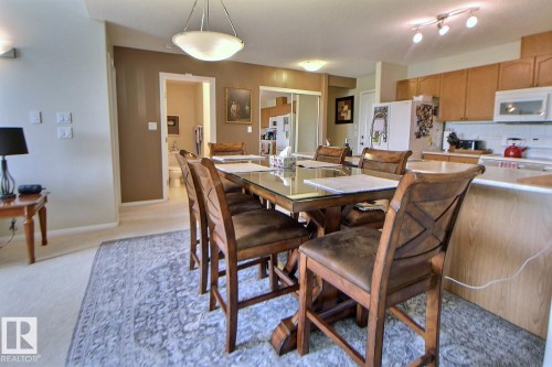 Recessed lighting and track lighting fixtures, wood-finish cabinetry, built-in kitchen appliances, and a pass-through kitchen counter - #421 592 Hooke Rd Nw, Edmonton, AB 