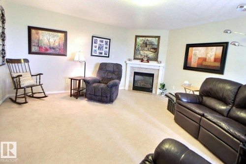 Corner gas fireplace with a tiled surround and white mantel - #421 592 Hooke Rd Nw, Edmonton, AB 