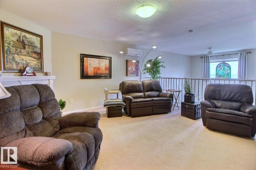 Carpeted open-concept room with a decorative railing - #421 592 Hooke Rd Nw, Edmonton, AB 