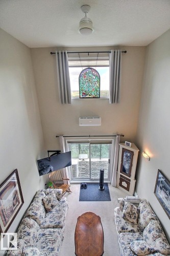 Vaulted ceiling with ceiling fan, a decorative stained glass window, and a wall-mounted mini-split system - #421 592 Hooke Rd Nw, Edmonton, AB 
