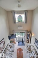 Vaulted ceiling with ceiling fan, a decorative stained glass window, and a wall-mounted mini-split system - 