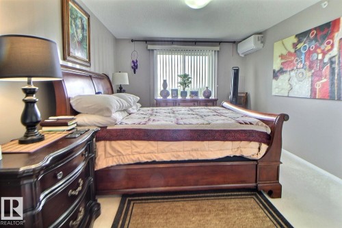 Wall-mounted mini-split AC unit, vertical blinds, and light-colored carpeting - #421 592 Hooke Rd Nw, Edmonton, AB 
