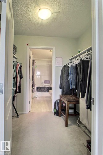 Recessed lighting illuminates the space, featuring carpeting and a doorway leading to an additional area - #421 592 Hooke Rd Nw, Edmonton, AB 