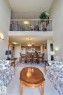 Open-concept living space featuring a high ceiling, an upper-level loft with a metal railing, and a kitchen with wood cabinetry and stainless steel appliances - #421 592 Hooke Rd Nw, Edmonton, AB 