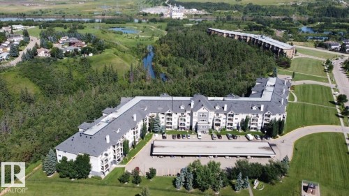 Multi-story building featuring dormer windows, covered parking, and an expansive paved lot - #421 592 Hooke Rd Nw, Edmonton, AB 