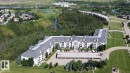 Multi-story building featuring dormer windows, covered parking, and an expansive paved lot - #421 592 Hooke Rd Nw, Edmonton, AB 