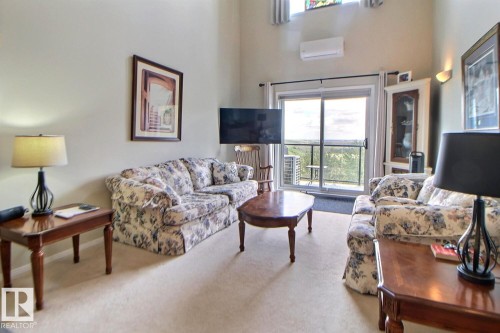 Vaulted ceiling, ceiling-mounted air conditioning unit, light wall color, carpeted flooring, and glass sliding doors leading to an outdoor space - #421 592 Hooke Rd Nw, Edmonton, AB 