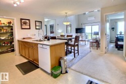 Kitchen island with integrated sink, light wood-finish cabinetry, and a built-in dishwasher - 