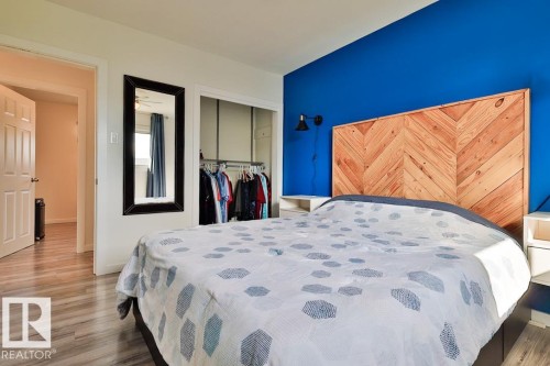Wood-finish flooring throughout, bright wall paint, built-in open closet, and a wooden chevron-patterned headboard - 13312 123A Street Nw, Edmonton, AB 