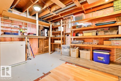 Unfinished basement space with exposed wood framing, comprehensive built-in shelving, and a concrete floor - 13312 123A Street Nw, Edmonton, AB 