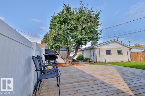 Expansive wood-plank deck with a white privacy fence and mature tree - 13312 123A Street Nw, Edmonton, AB 