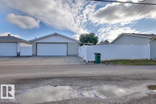 Two separate garages with white panel doors, one featuring a gable roof and the other a hip roof - 13312 123A Street Nw, Edmonton, AB 