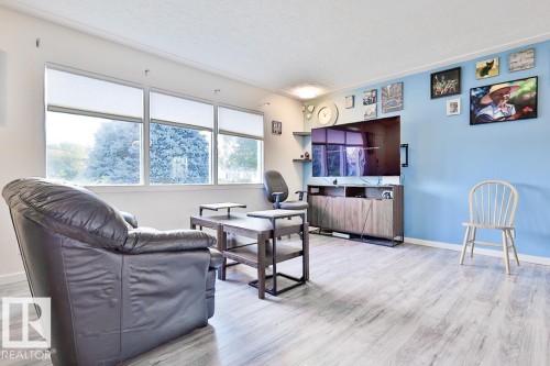 Light wood-finish flooring, accent wall, built-in shelving, and multiple windows with shades - 13312 123A Street Nw, Edmonton, AB 