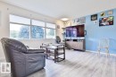 Light wood-finish flooring, accent wall, built-in shelving, and multiple windows with shades - 13312 123A Street Nw, Edmonton, AB 