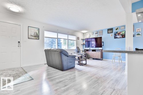 Wood-finish flooring throughout, multiple large windows, recessed lighting, and a built-in breakfast bar with a solid surface countertop - 13312 123A Street Nw, Edmonton, AB 
