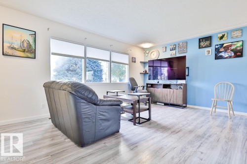 Wood-finish flooring throughout, bright white walls, and a light blue accent wall - 13312 123A Street Nw, Edmonton, AB 