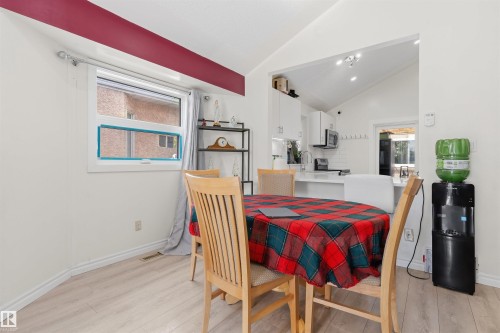 Open-concept dining area with wood-finish flooring, a vaulted ceiling, and a large window - 4824 13 Avenue Nw, Edmonton, AB 