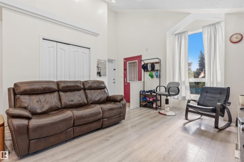 Vaulted ceiling with crown molding, wood-finish flooring, bay window, and a red entry door with transom window - 4824 13 Avenue Nw, Edmonton, AB 