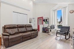 Vaulted ceiling with crown molding, wood-finish flooring, bay window, and a red entry door with transom window - 