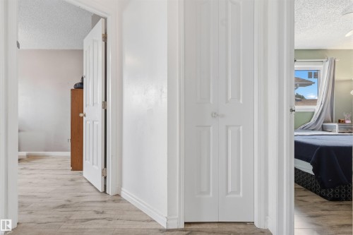 Wood-finish flooring throughout the hallway, featuring white paneled doors and a bi-fold closet - 4824 13 Avenue Nw, Edmonton, AB 