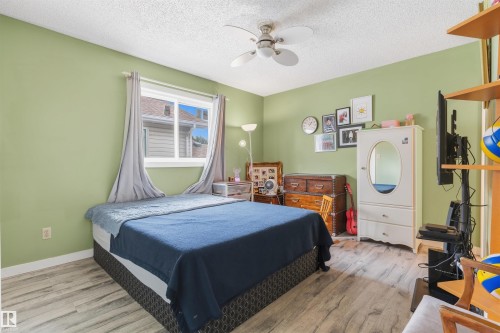 Window with white trim, wood-finish flooring, ceiling fan with integrated lighting, built-in shelving, and light green wall paint - 4824 13 Avenue Nw, Edmonton, AB 