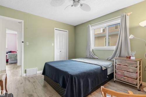 Light wood-finish flooring, white bi-fold closet doors, and a ceiling fan with integrated lighting - 4824 13 Avenue Nw, Edmonton, AB 