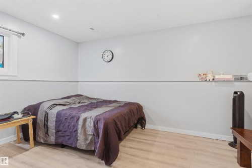 Light-toned wood-finish flooring, recessed ceiling lighting, and a window with white trim - 4824 13 Avenue Nw, Edmonton, AB 