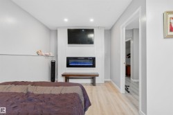 Integrated electric fireplace with a white surround, recessed lighting, and wood-finish flooring - 