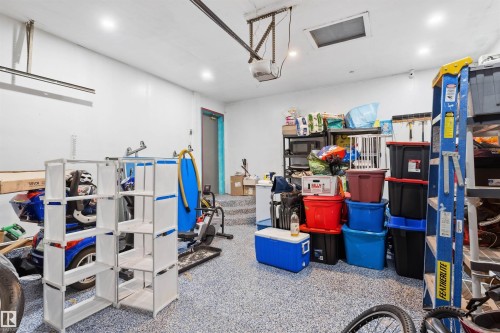 Finished garage space featuring a speckled epoxy floor, recessed lighting, and a utility door - 4824 13 Avenue Nw, Edmonton, AB 