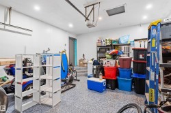 Finished garage space featuring a speckled epoxy floor, recessed lighting, and a utility door - 