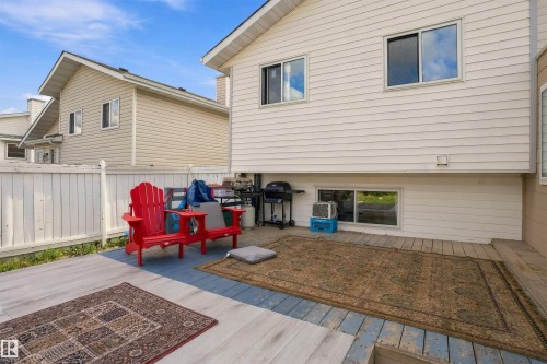 Spacious outdoor deck with wood-finish flooring, white privacy fencing, and multiple windows - 4824 13 Avenue Nw, Edmonton, AB 