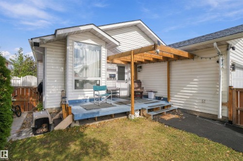 White siding exterior with a wood pergola, attached garage, and a raised wood deck - 4824 13 Avenue Nw, Edmonton, AB 