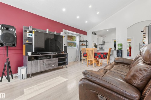 Vaulted ceilings enhance the main living space with recessed lighting, wood-finish flooring, and a distinct accent wall - 4824 13 Avenue Nw, Edmonton, AB 
