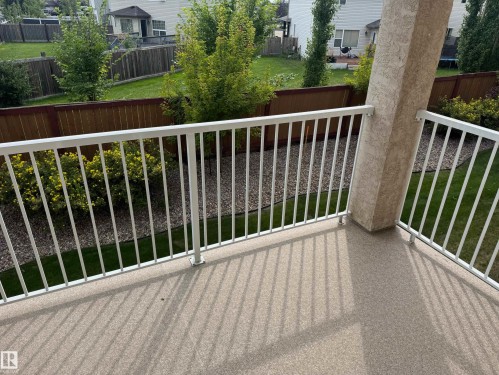 Balcony featuring a textured floor, white metal railing, and a stucco-finished support column - #229 2305 35A Av Nw, Edmonton, AB 