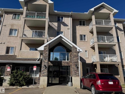 Multi-story building featuring a stone-clad entry, stucco exterior, and multiple private balconies with white railings - #229 2305 35A Av Nw, Edmonton, AB 
