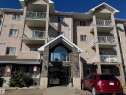 Multi-story building featuring a stone-clad entry, stucco exterior, and multiple private balconies with white railings - #229 2305 35A Av Nw, Edmonton, AB 