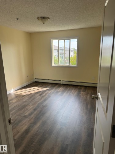 Wood-finish flooring with a smooth texture, bright white trim, and a ceiling-mounted light fixture - #229 2305 35A Av Nw, Edmonton, AB 