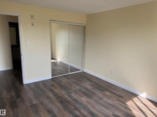 Wood-finish flooring with light-toned walls and mirrored closet doors - #229 2305 35A Av Nw, Edmonton, AB 