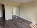 Wood-finish flooring with light-toned walls and mirrored closet doors - #229 2305 35A Av Nw, Edmonton, AB 