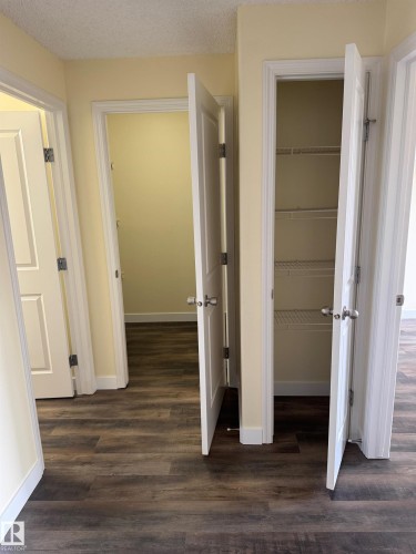 Wood-finish flooring throughout, multiple paneled doors, and a built-in wire shelving unit - #229 2305 35A Av Nw, Edmonton, AB 