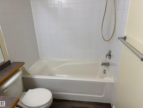 White tile shower surround with a built-in bathtub and chrome fixtures - #229 2305 35A Av Nw, Edmonton, AB 
