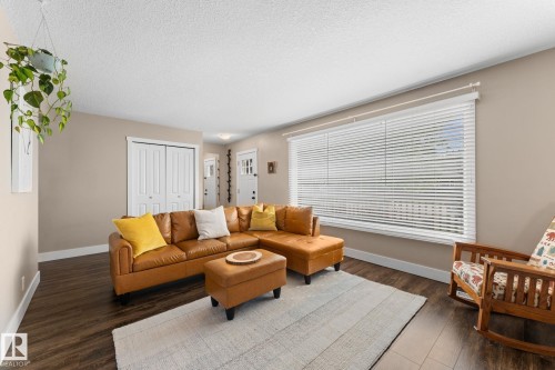 Spacious room featuring laminate flooring, neutral wall tones, a large window with blinds, and white bi-fold closet doors - 6108 102 Avenue Nw, Edmonton, AB 